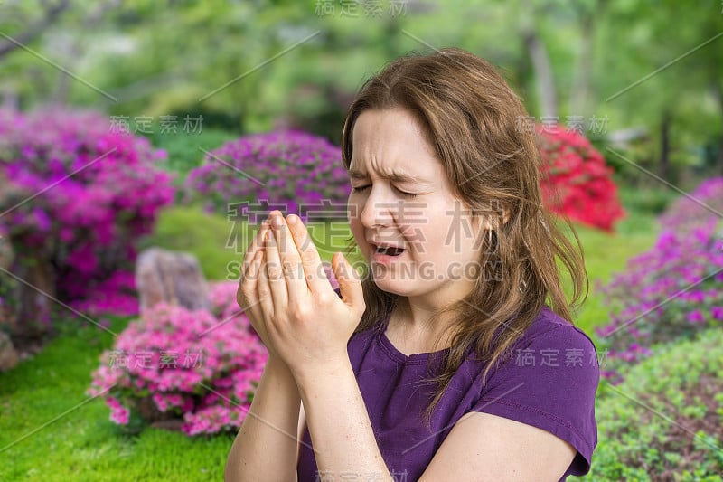 花粉过敏的概念。年轻女子要打喷嚏了。花在后台。