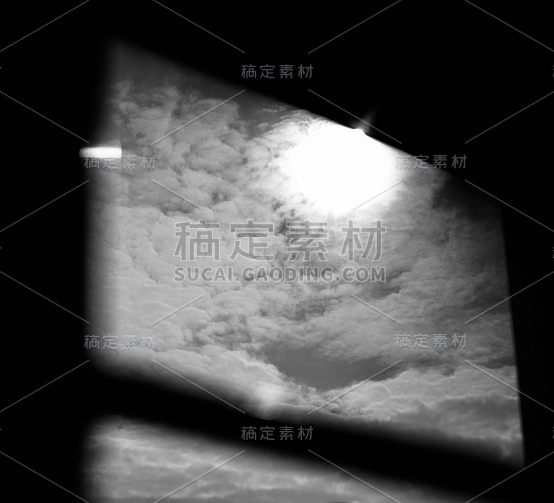 透过窗户可以看到天空、云朵和太阳，黑白照片