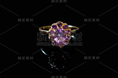 美丽的金色戒指与紫色宝石孤立在黑色背景