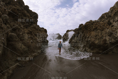 女孩站在沙滩上玩海浪在阴天