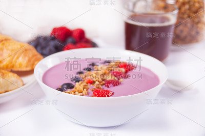 草莓奶昔碗。羊角面包，旁边有一杯咖啡。
