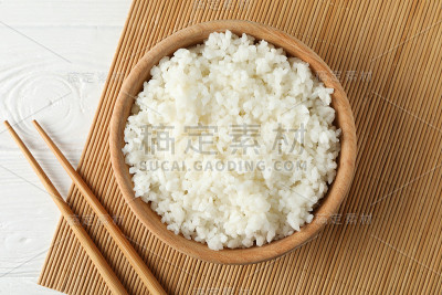 碗与煮米饭和筷子在木背景，俯视图