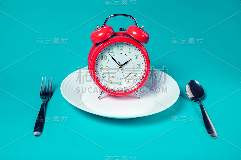 闹钟在白色板上的彩色背景。保健和食品概念