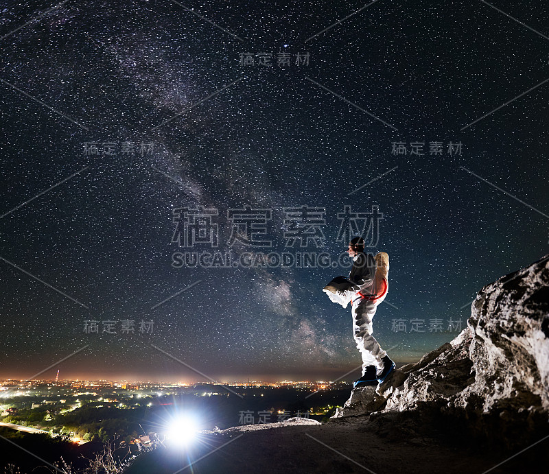 宇航员站在岩石山下，星空灿烂。