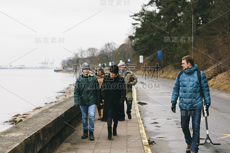 在寒冷的冬天，一家人穿着冬装走在海边的街道上——爷爷奶奶、爸爸、儿子