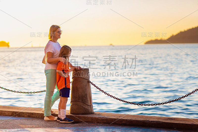日落时分，母亲和孩子在海边。