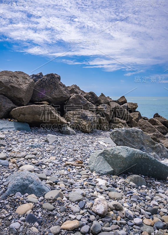 海滨景观卵石和防波堤石头在前景和清晰的地平线和天空在背景。夏季休闲活动，旅游度假。