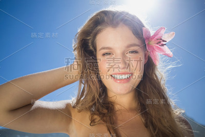 美丽的微笑金发与花发饰在海滩上