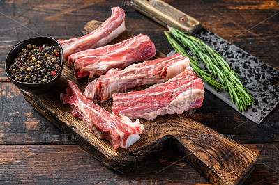 生的小牛肉切成薄片，放在木砧板上。黑色背景。俯视图