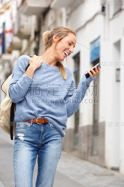 一个快乐的年轻女人带着手机走在城市里