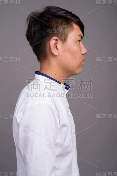 工作室拍摄的年轻亚洲十几岁的男孩看起来正式的灰色背景