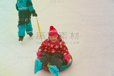 小男孩滑板推快乐的姐姐在管，孩子们冬天的乐趣
