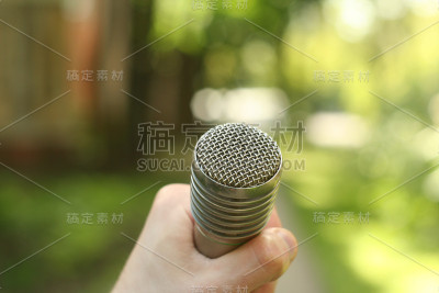 手拿麦克风。在公园采访。