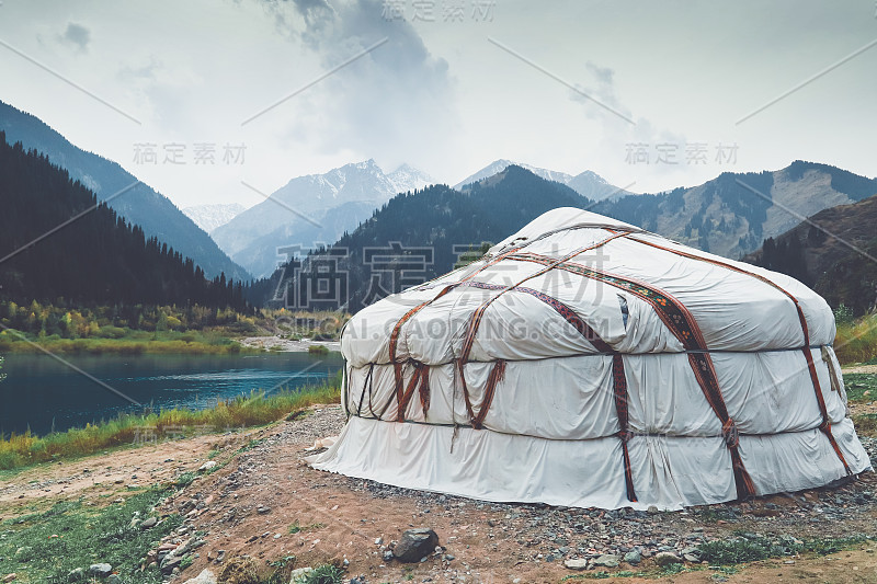 哈萨克斯坦山区湖上的帐篷。白雪皑皑的山峰。