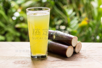 甘蔗汁与一块甘蔗在木制背景