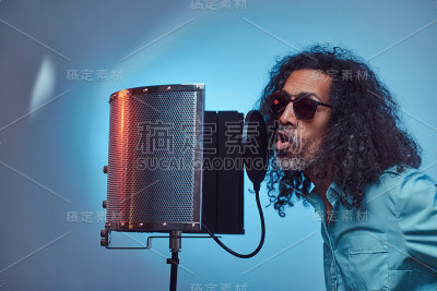 非洲声乐艺术家穿着一件蓝色衬衫情绪化地写歌在录音室。