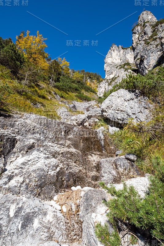 阳光灿烂的高山秋景。上奥地利阿尔姆西湖附近徒步旅行的宁静岩石山景。