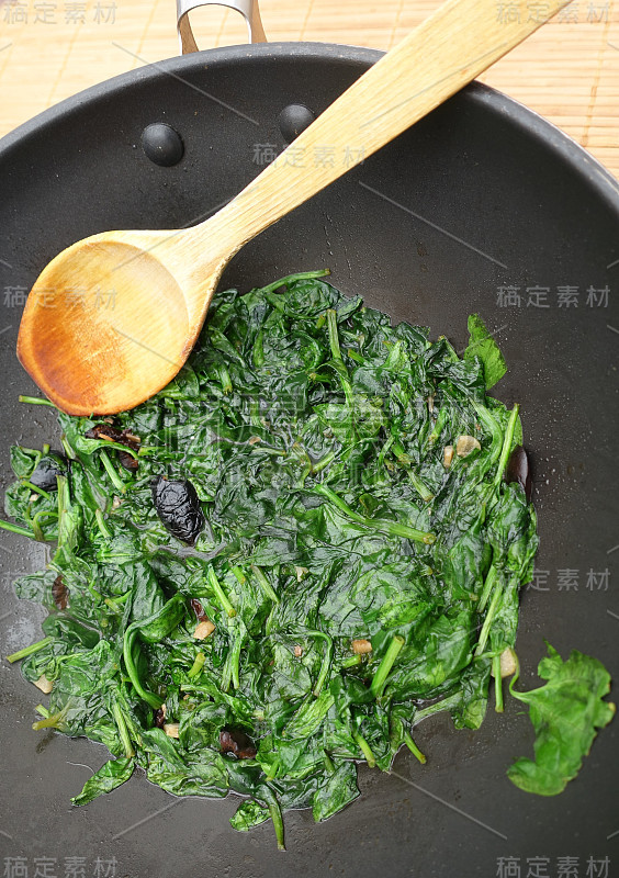 嫩菠菜芽与黑橄榄和凤尾鱼一起在锅中烹饪