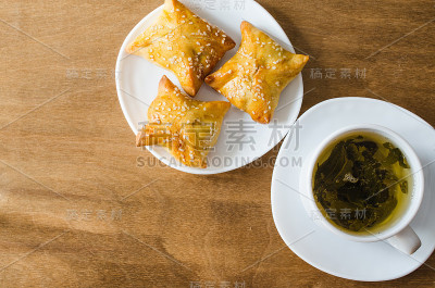 质朴的木桌上放着绿茶和馅饼