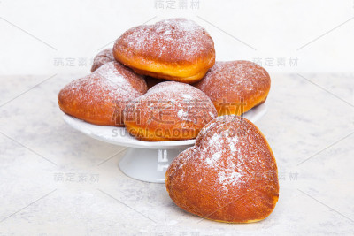 白色背景上撒着糖粉的自制心形甜甜圈。美味的甜甜圈，拷贝空间