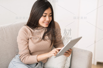 有趣的内容。一个亚洲女孩在平板电脑上阅读博客