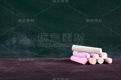 彩色粉笔堆在绿色黑板的木桌上