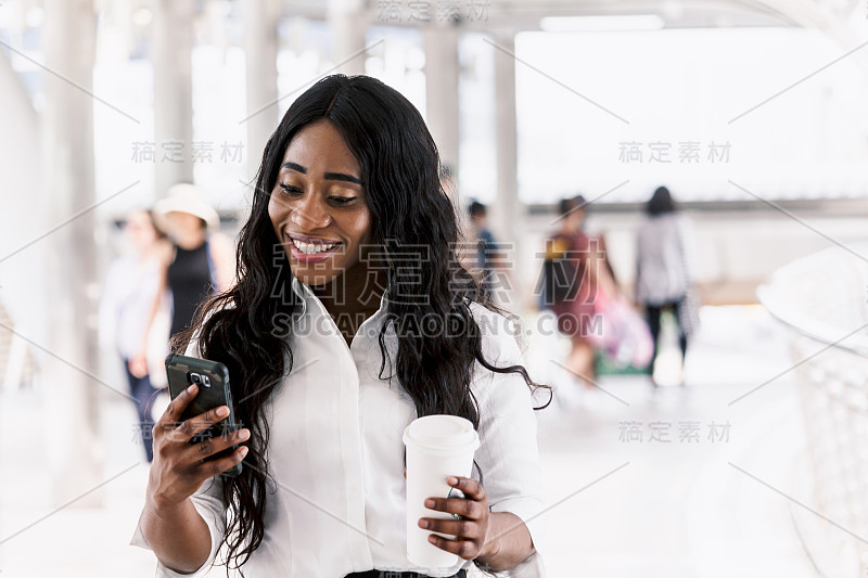 拿着咖啡和智能手机的非裔美国女人