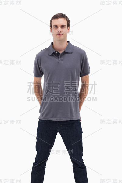 一个站着的男人与他的手背后和他的腿分开的特写