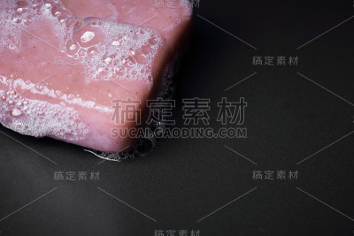 在黑暗的背景上一个泡沫粉红色肥皂棒的特写