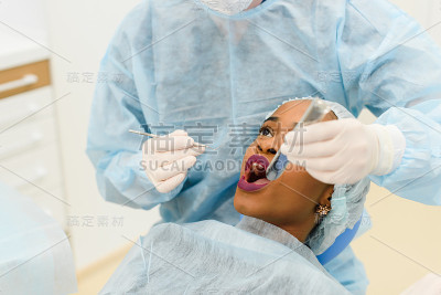 牙医与助理穿制服的医疗程序女性病人