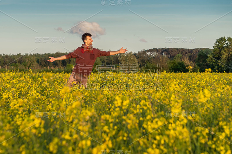 年轻人张开双臂，在油菜田里感受自由