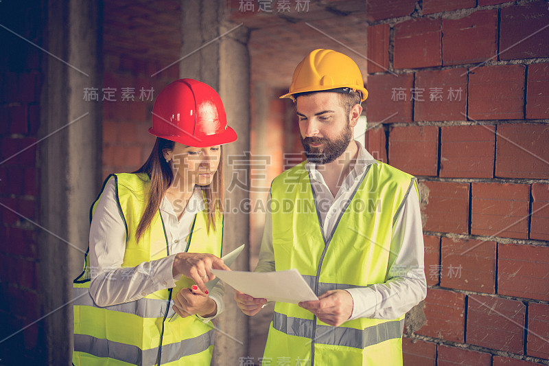 年轻女建筑师向工人展示设计图