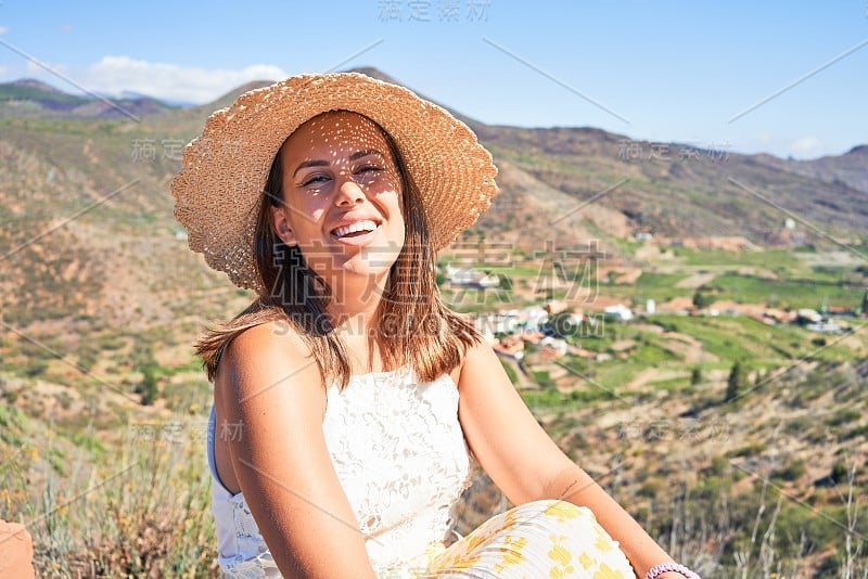 年轻美丽的女子在山上享受着暑假的风景，旅行者女孩笑得很开心