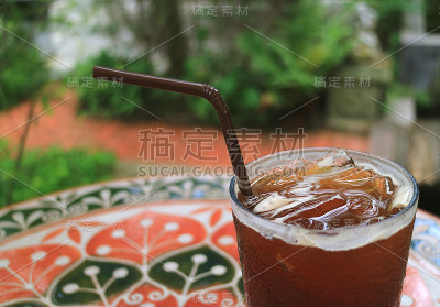 一杯冰黑咖啡放在花园露台的桌子上，模糊的背景