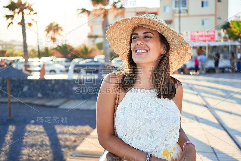 年轻漂亮的女人微笑着愉快地在海滩上享受暑假