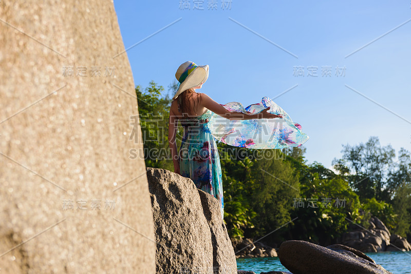 妇女们站在海滩上的一块岩石上