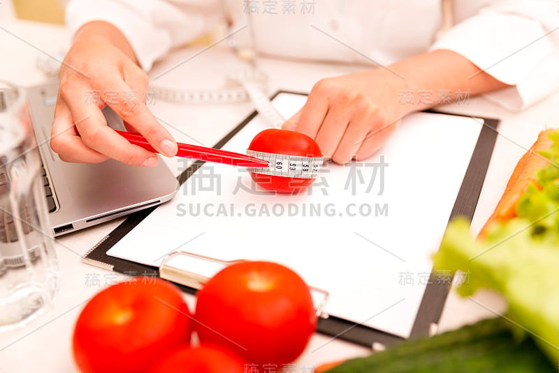 蔬菜饮食营养或药物概念。女营养医生拿着蔬菜和卷尺放在桌上