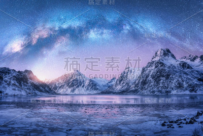 冬日夜晚，挪威罗浮敦群岛冰雪覆盖的山脉和海岸上空的银河。北极景观有蓝色的星空、水、冰、雪石、银河。空