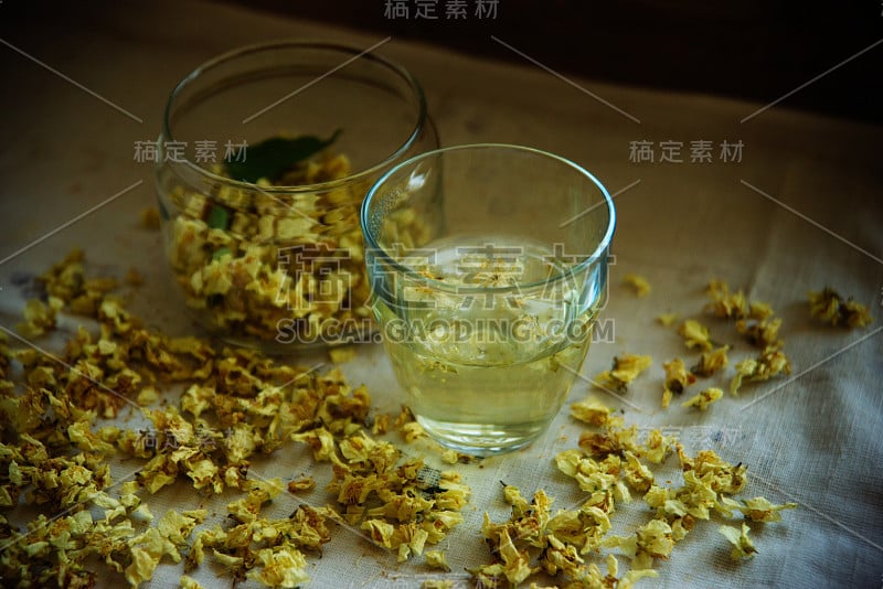 绿色背景木桌上的茉莉花绿茶杯和茶壶