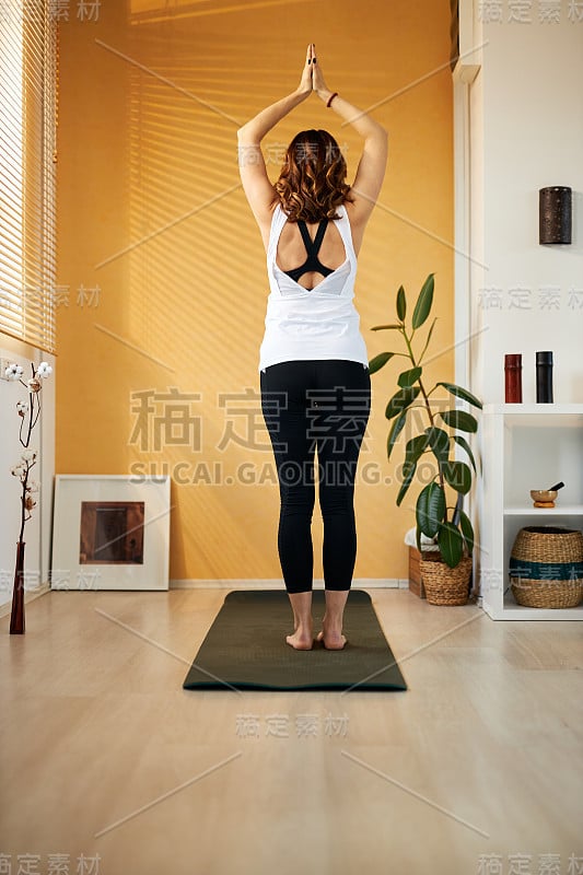 后视图的fit yogi妇女站在她的家的垫子新月瑜伽姿势。