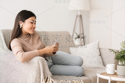 休闲活动。坐在沙发上听音乐的女孩