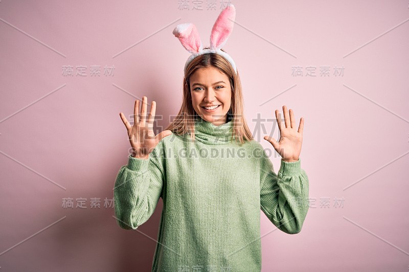 年轻美丽的女人戴着复活节兔子耳朵站在孤立的粉红色背景显示和指向10号手指，同时自信和快乐的微笑。