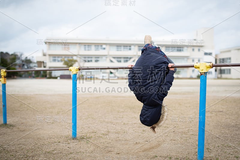 在操场上玩单杠的女孩