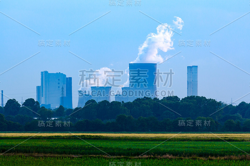 绿色多汁的草在灰色褐煤发电厂前