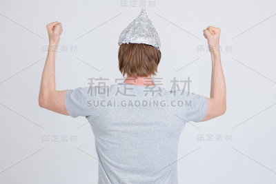 后视图的年轻人与锡纸帽阴谋论概念举起拳头