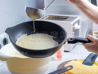 面糊从金属桶中倒入烧红的油煎锅中。烤薄饼的过程。