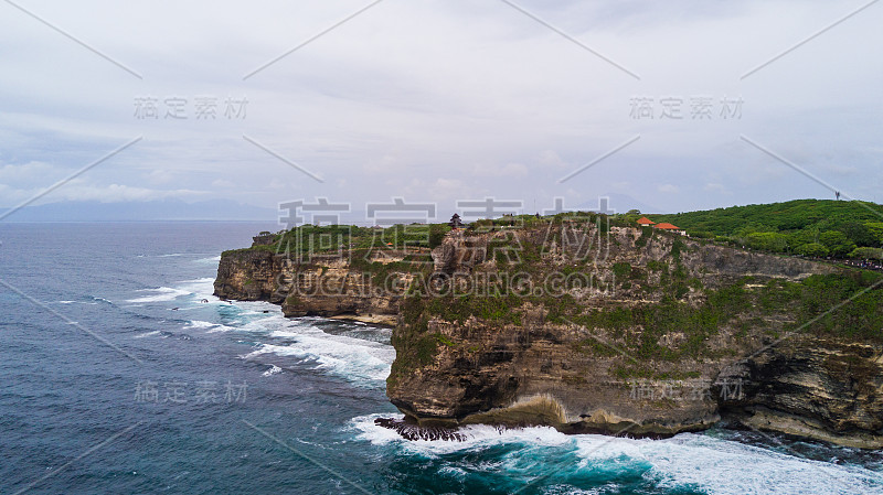 海上岩石海岸与冲浪的海浪鸟瞰图，巴厘岛，印度尼西亚，普拉乌鲁瓦图悬崖。海浪冲击着岩石海岸。海景、岩石