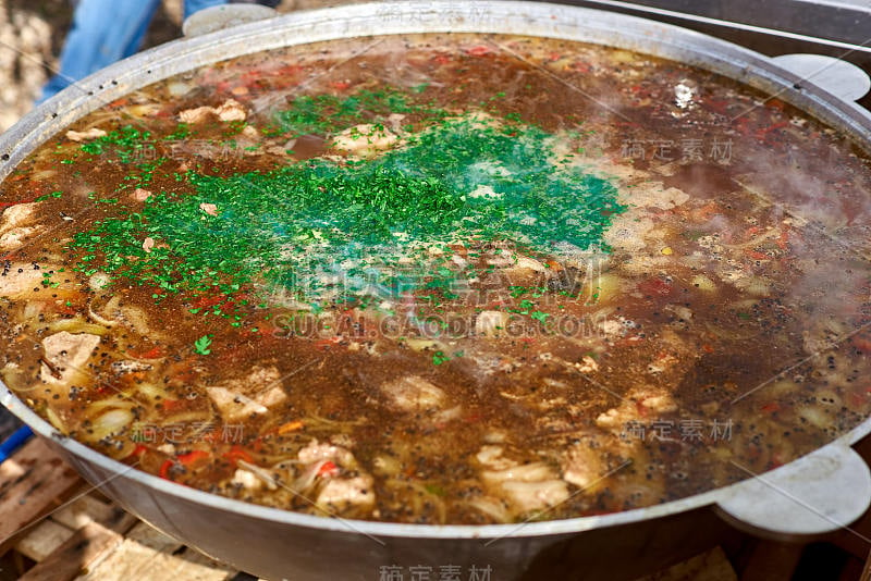 在露天用大锅熬羊肉汤的过程。