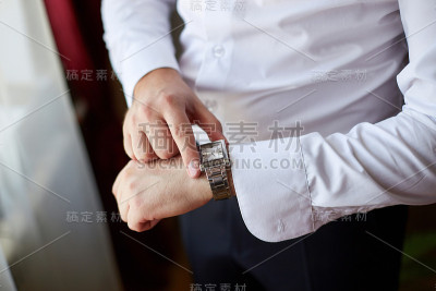 穿着深色西装的新郎戴上一块手表，特写镜头
