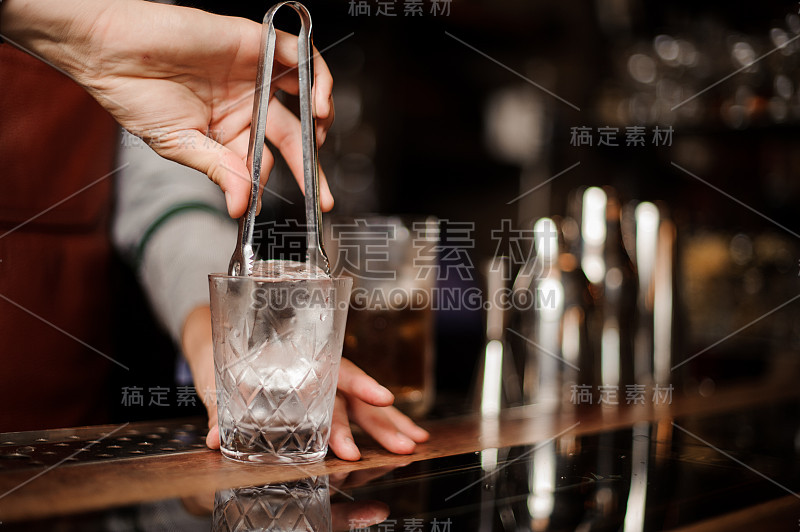 酒保正在把冰块放进小酒杯